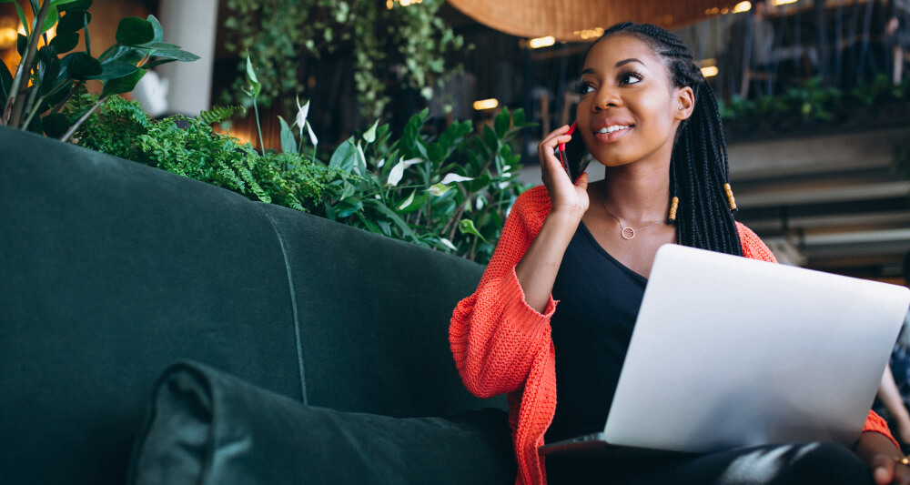 african american woman with phone laptop cafe