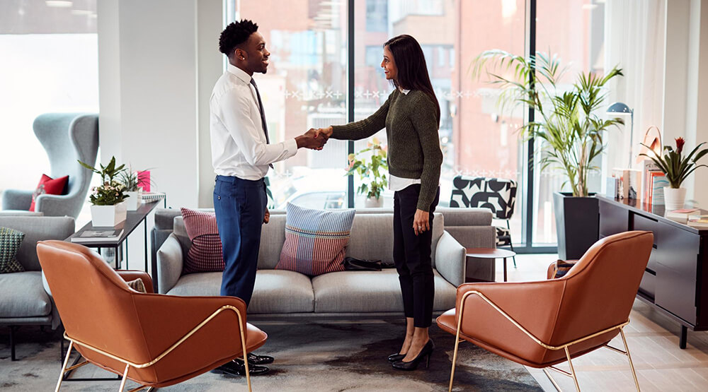 businesswoman shaking hands with male interview candidate seating area modern office